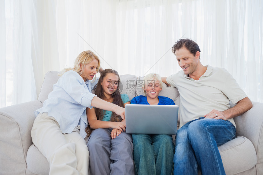 家庭在使用笔记本电脑时坐在沙发上图片