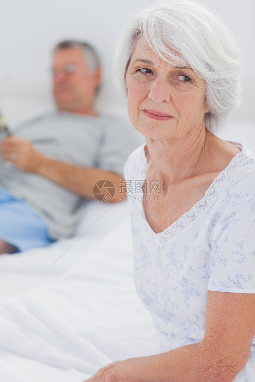 坐在床上的焦虑成年妇女夫妻男性卧室羽绒被流金白色岁月睡衣公寓女性图片