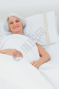妇女在床上休息住所午睡坐垫岁月房子退休苏醒被子说谎女士背景图片