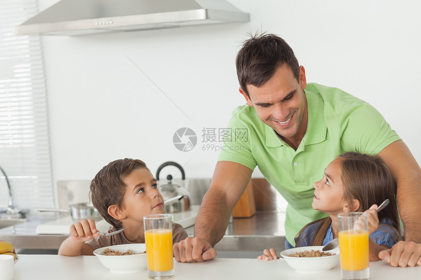 父亲在孩子吃早饭时 与他们的孩子们交谈图片