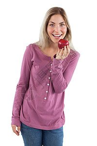 开心的女士展示一个苹果饮食浅色金发牛仔布水果牛仔裤长发头发红色女性背景图片
