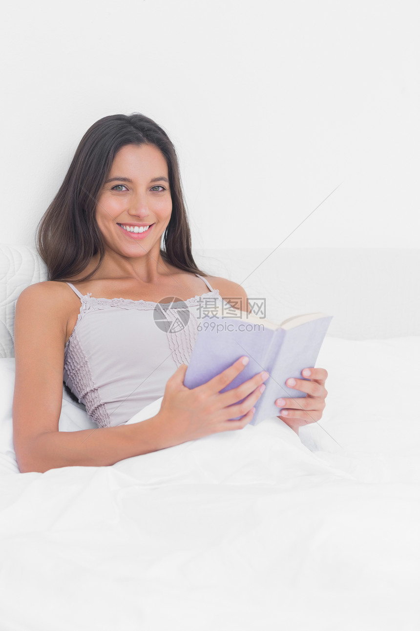 一个女人在床上看 拉皮书 的肖像图片