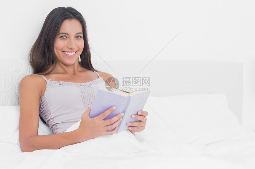 一个女人在床上看书的肖像图片