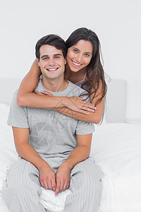 拥抱其伴侣的妇女坐在床上高清图片