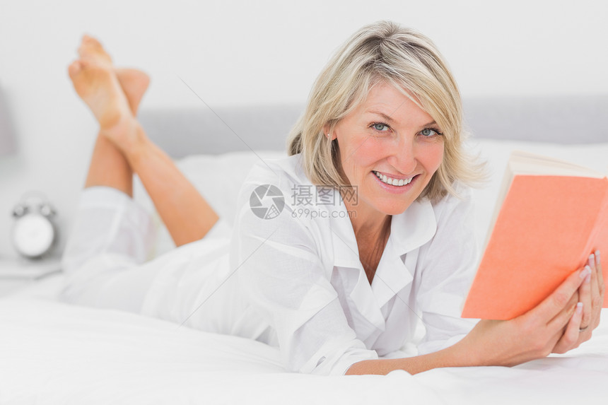 快乐的女人在床上看一本书图片