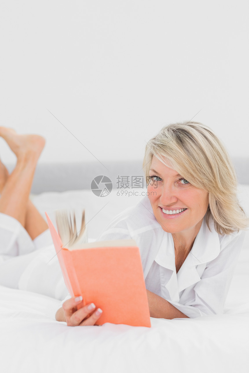 金发女人在看一本躺在床上的书图片