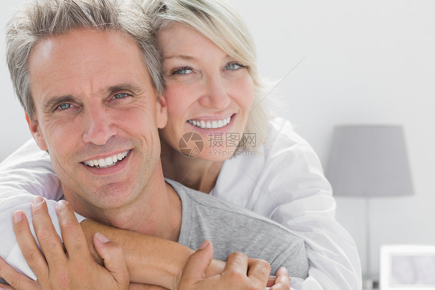 情侣对着镜头微笑金发女郎头发女士快乐女性公寓睡衣浅色夫妻房子图片