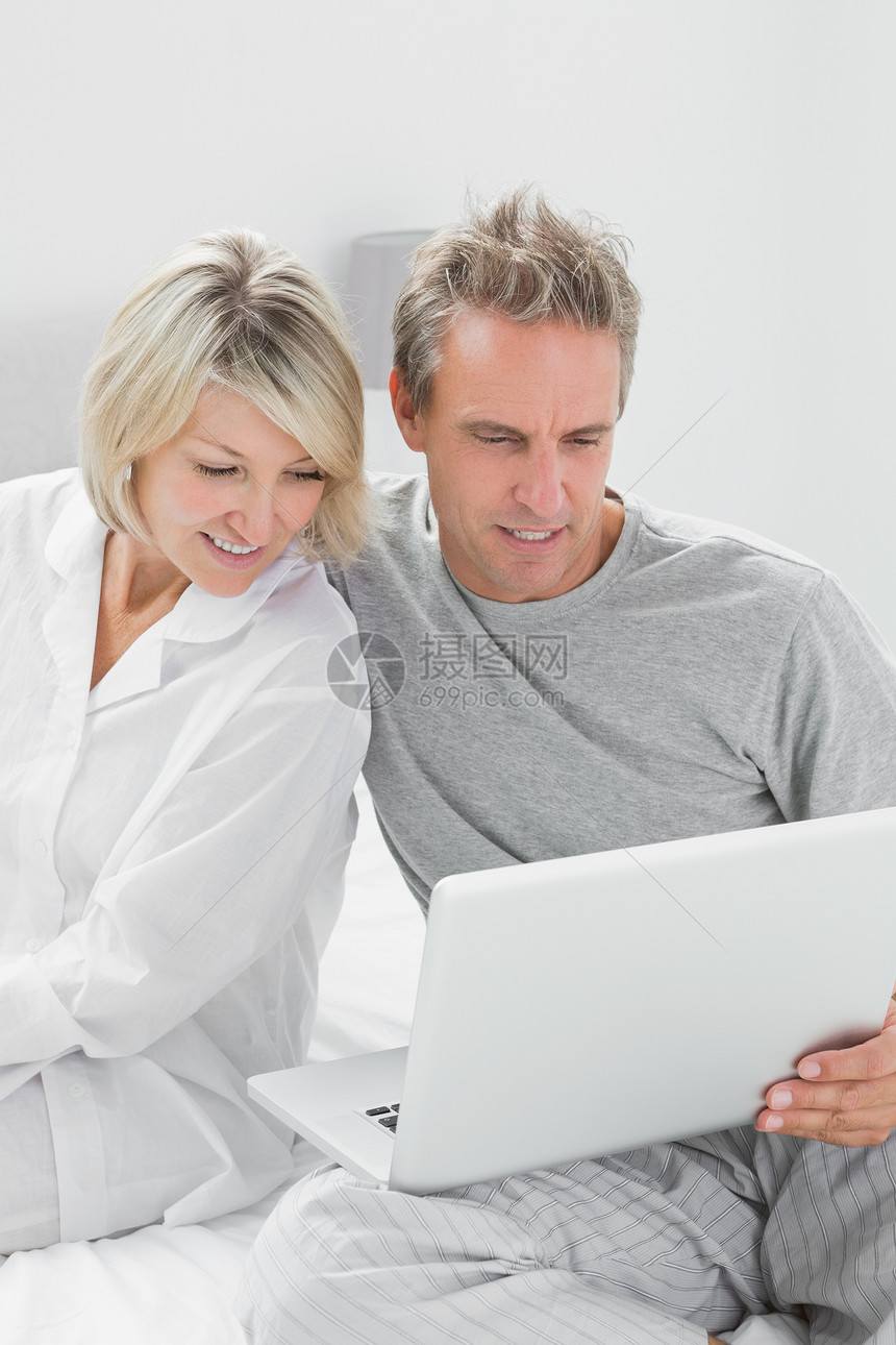 夫妇在床上使用笔记本电脑图片
