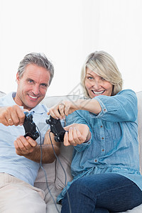 在沙发上玩电子游戏的情侣头发闲暇感情控制器房子夫妻按钮家庭微笑男人背景图片