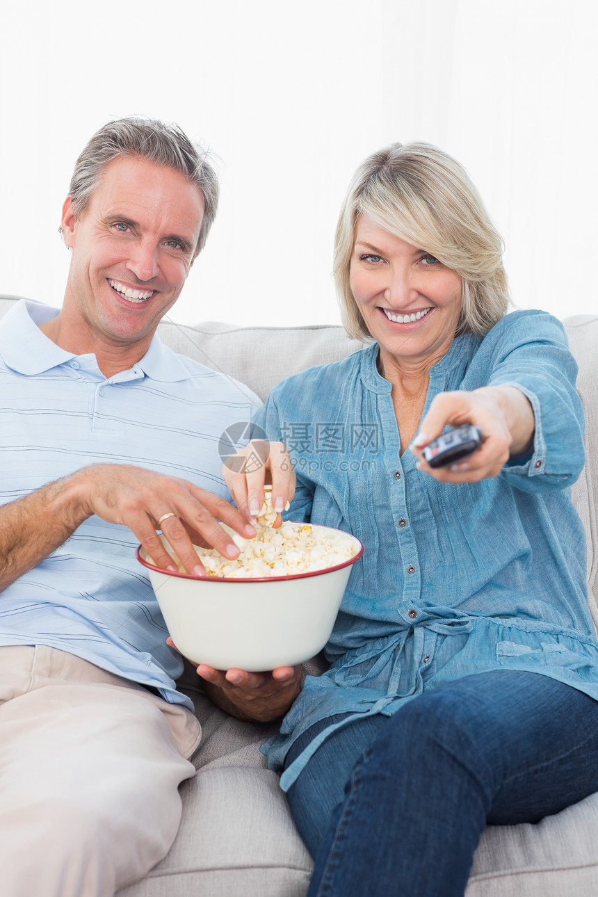 一对夫妇在沙发上看电视 吃爆米花图片