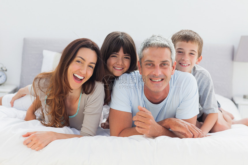 幸福的一家人一起躺在一起公寓枕头父亲家庭感情拥抱房子女儿微笑儿子图片