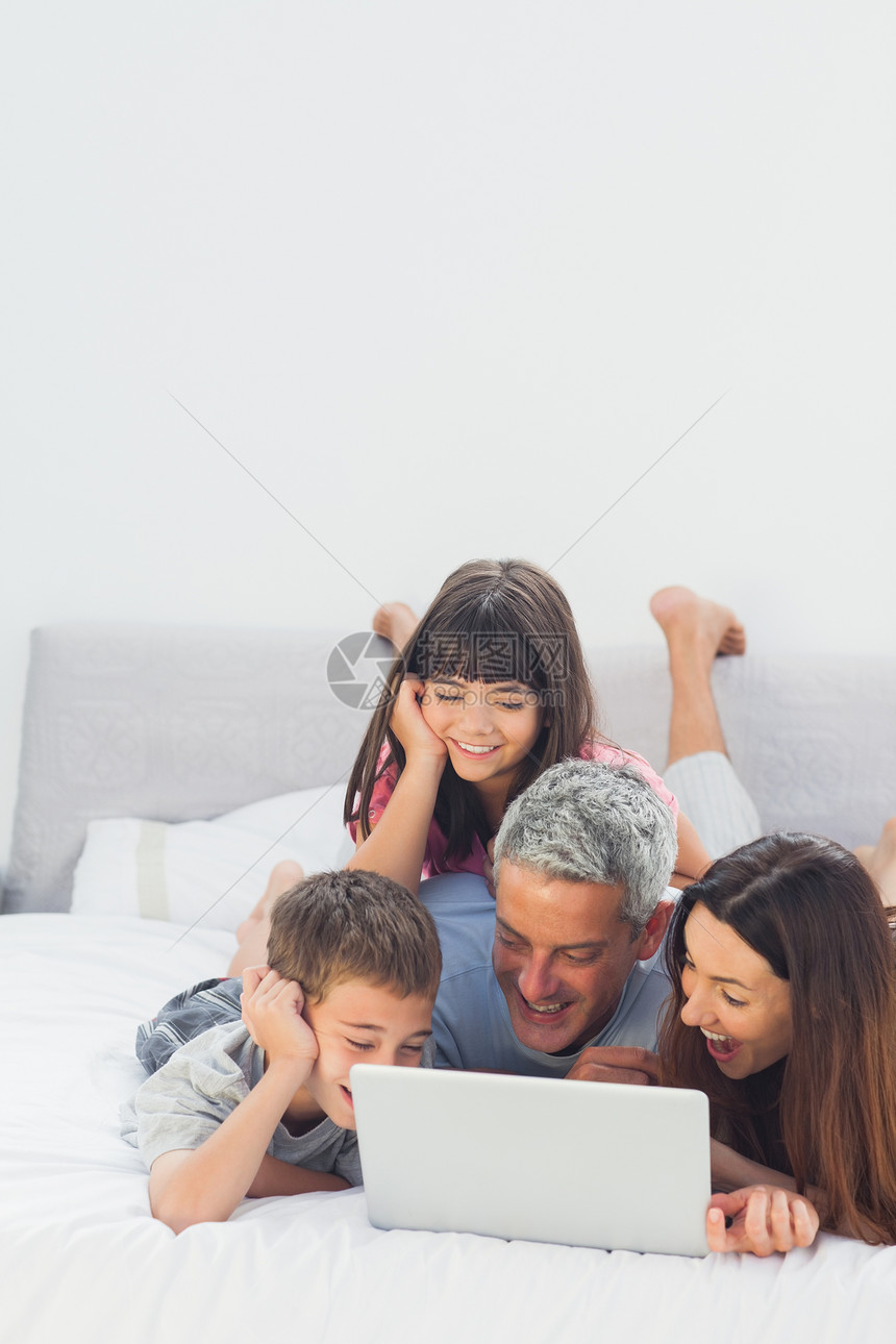 幸福的家庭用笔记本电脑躺在床上女儿房子儿子讨论女孩棕色快乐感情公寓住所图片