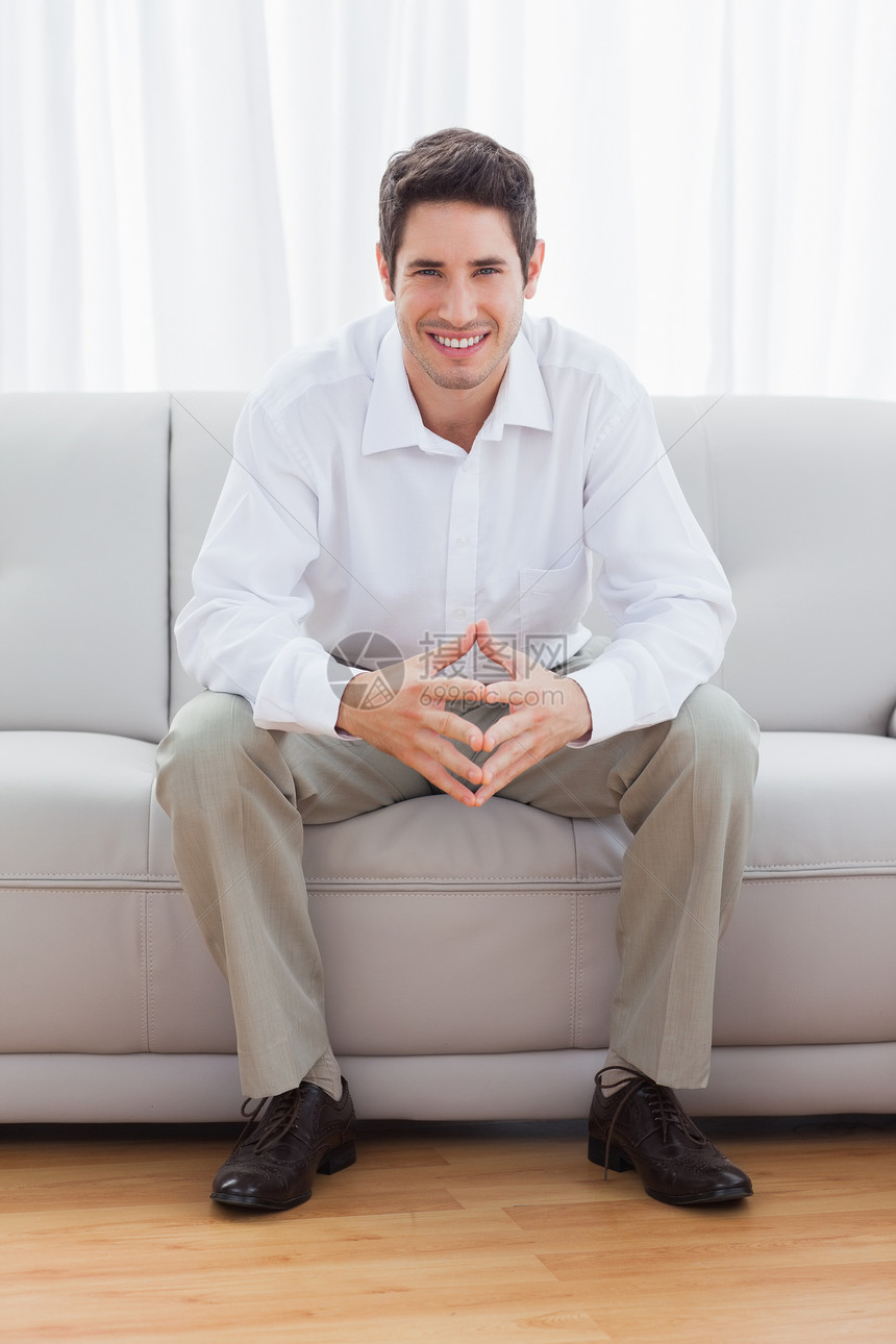 坐在沙发上的年轻人男性微笑住所长椅棕色衬衫房子短发男人客厅图片
