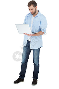 使用笔记本电脑微笑的男人牛仔裤男性快乐衬衫技术牛仔布背景图片