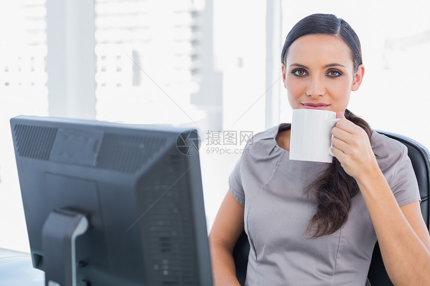 放松的有吸引力的女商务人士喝茶图片