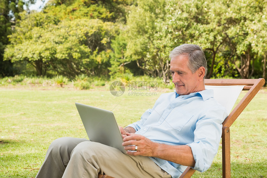使用笔记本电脑微笑的成熟男子公园男人阳光草原享受农村快乐岁月绿地晴天图片