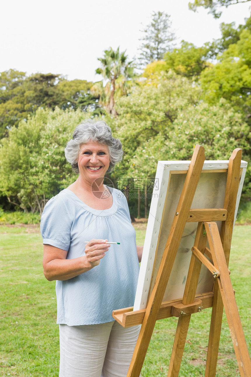 幸福的退休女性在画布上绘画图片
