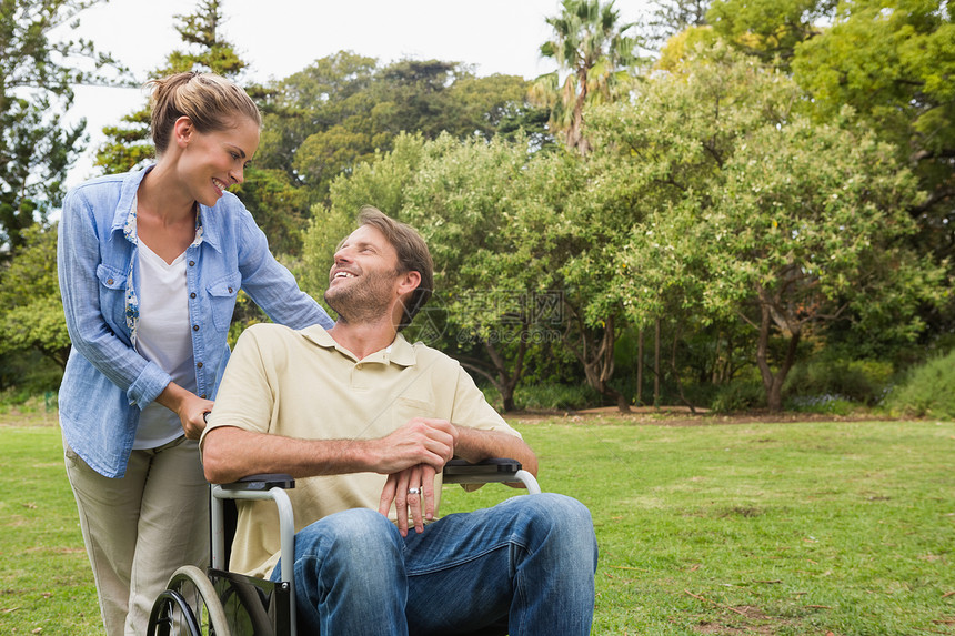 坐在轮椅上微笑的男人与伴侣交谈图片
