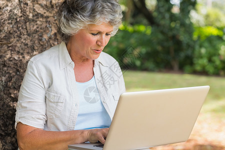 带笔记本电脑的灰色头发女人背景图片