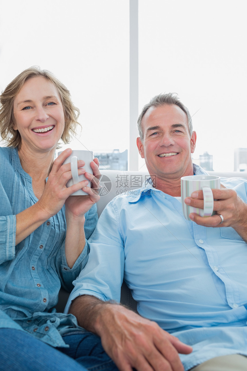 坐在沙发上喝咖啡的中年快乐情侣图片