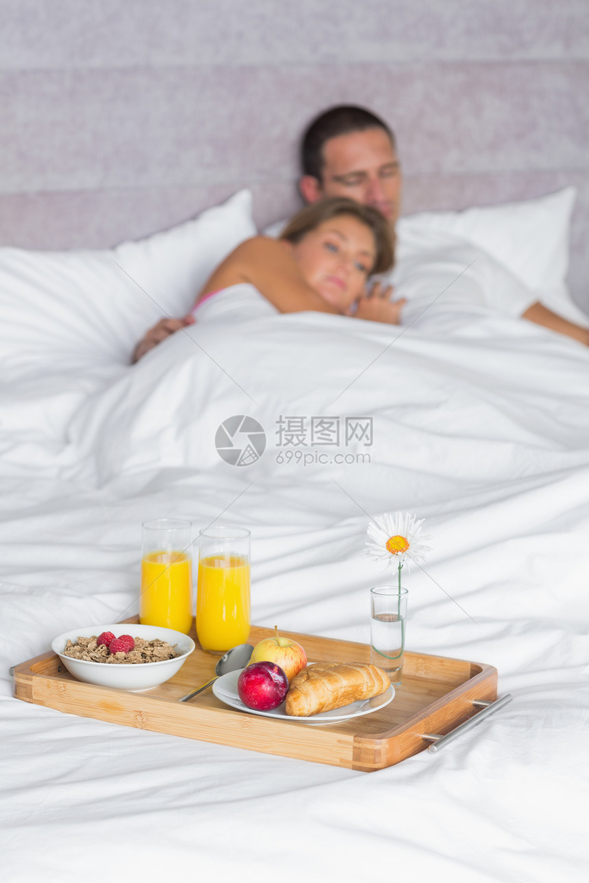 有吸引力的夫妇睡着 床上有早餐盘图片