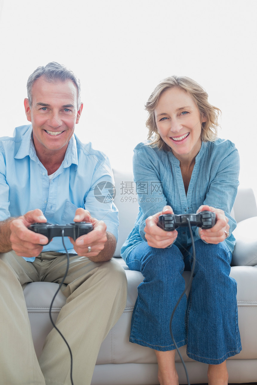 在沙发上玩电子游戏的一对微笑的情侣图片