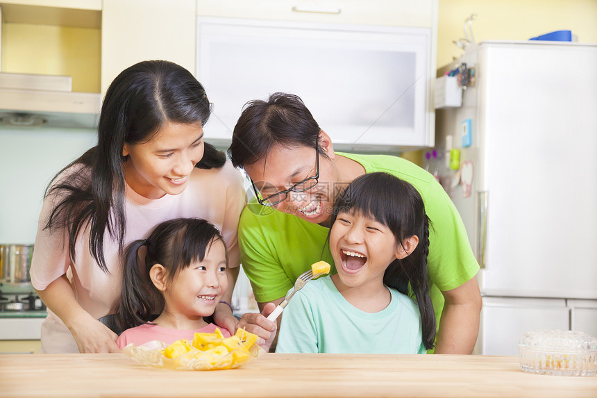幸福的家庭和女儿在厨房里吃着水果图片