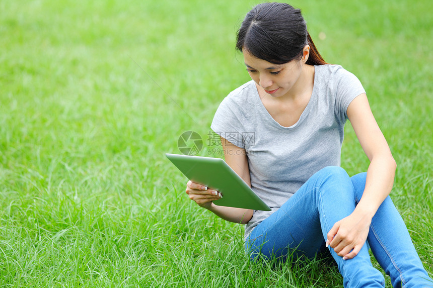 使用平板电脑坐在草地上的妇女大学青少年女性学生技术黑发说谎青年快乐女孩图片
