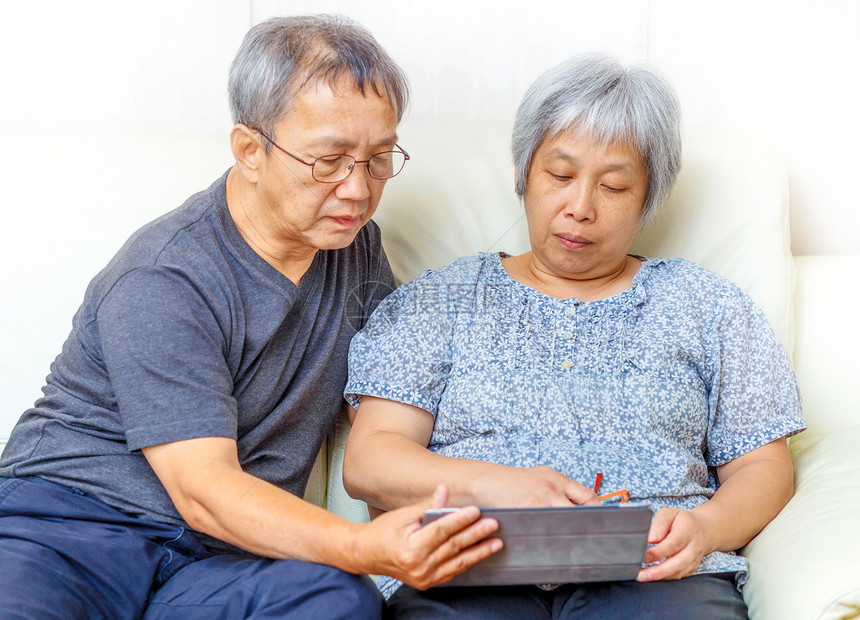 使用数字平板电脑的亚洲老年夫妇老夫妻男人白色女性灰色头发学习药片夫妻两个人图片