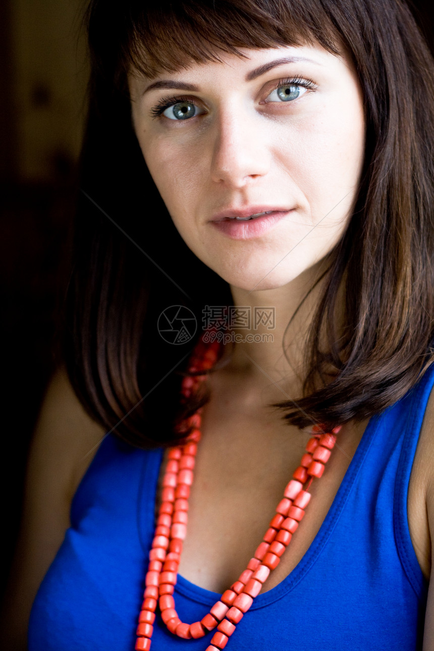 一个美丽的年轻黑发美女的肖像 红色珠珠子悲伤蓝色女性眼睛图片