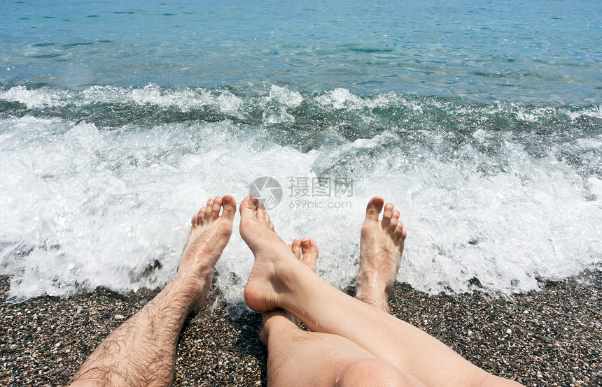 沙滩上的对等双腿生活成年人闲暇男人鹅卵石夫妻海浪休闲游客皮肤图片