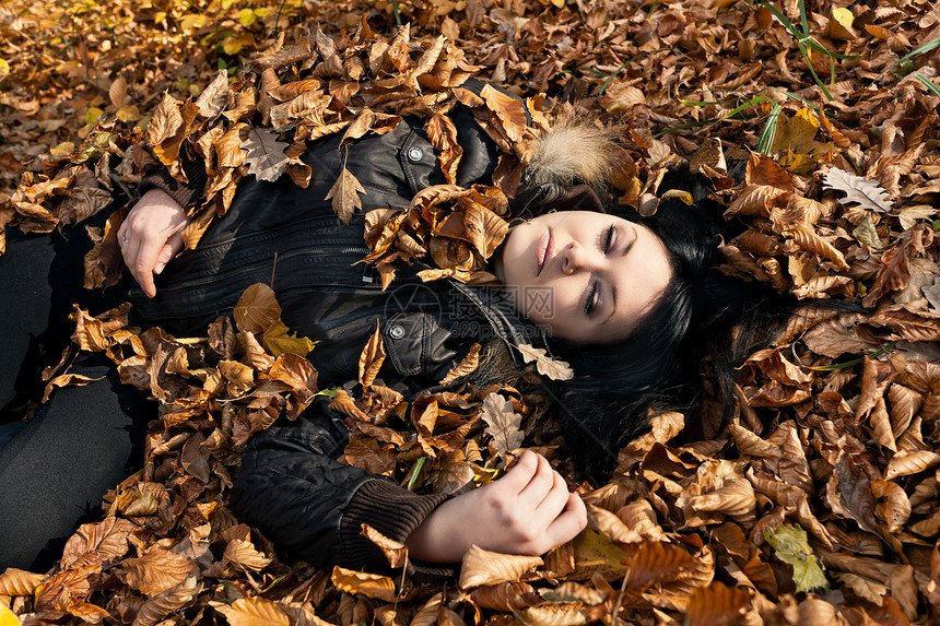 躺着落叶的女人头发森林休息女性阳光地面叶子季节青少年眼睛图片