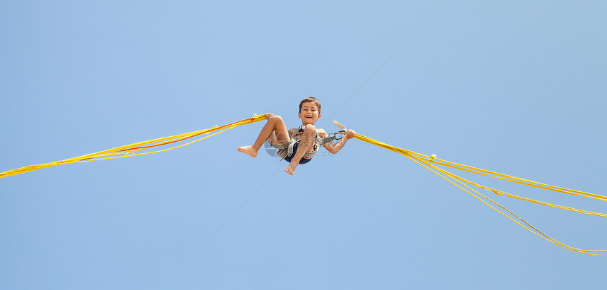 男孩跳跃在蹦床线上乐趣逗乐活动灵活性天空游乐场幸福行动运动娱乐图片
