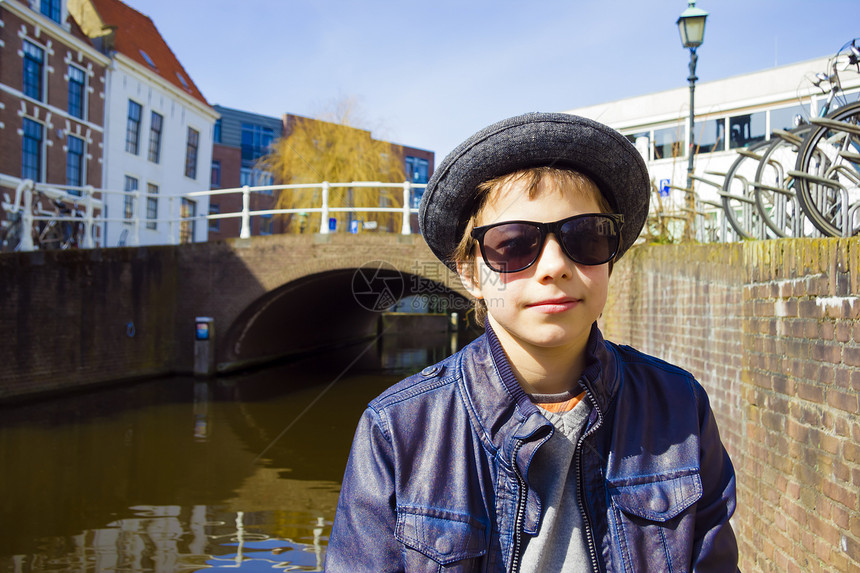 身着墨镜的帅男孩 面对运河背景乐趣微笑衣服帽子蓝色夹克靴子季节男性阳光图片