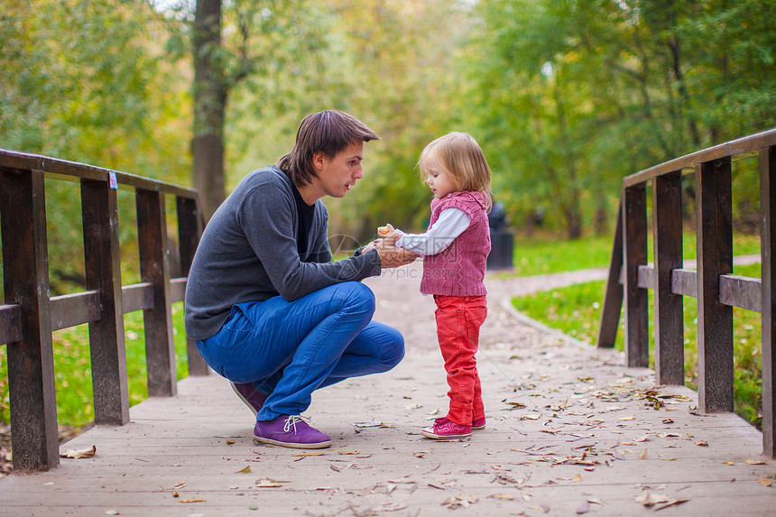 年轻父亲和他可爱的小女儿 在秋天公园家庭孩子花园休息室男人婴儿叶子感情父母拥抱图片
