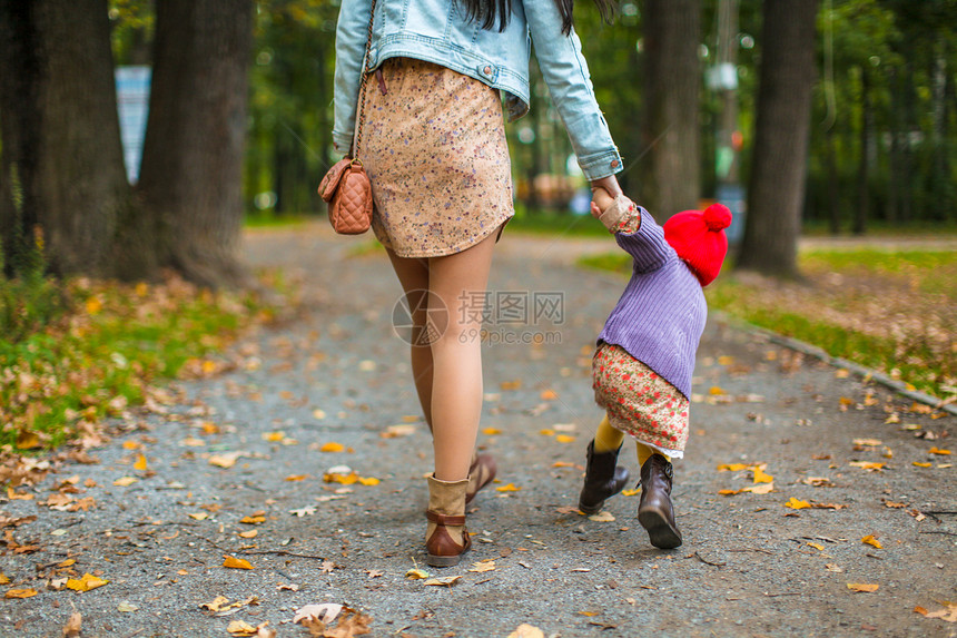 年轻母亲与女儿一起在秋天公园散步的背影图片