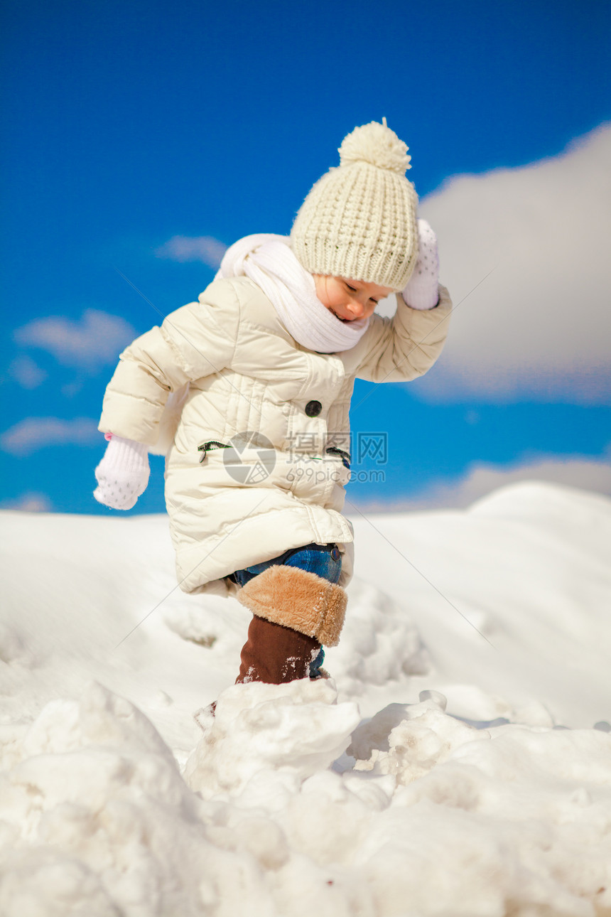 快乐的小女孩在雪中走 在阳光明媚的冬日图片