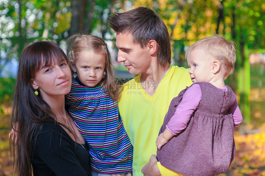 年轻迷人家庭的肖像 有两个孩子 在黄色秋天公园享受着风景图片