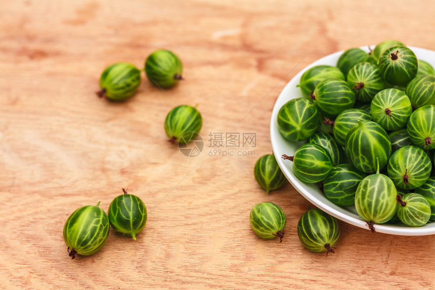 将鹅莓贴近在木质桌上的白色白菜桌桌子水果甜点盘子食物饮食早餐美食浆果烹饪图片