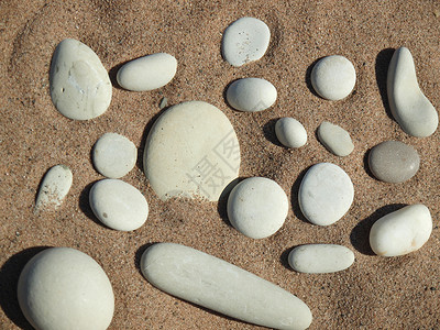泥石和沙砂白色圆形石头海岸黑色太阳季节灰色湖泊背景图片