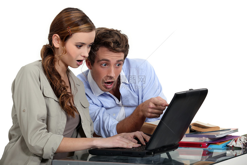 惊吓的一对夫妇指着一台笔记本电脑图片