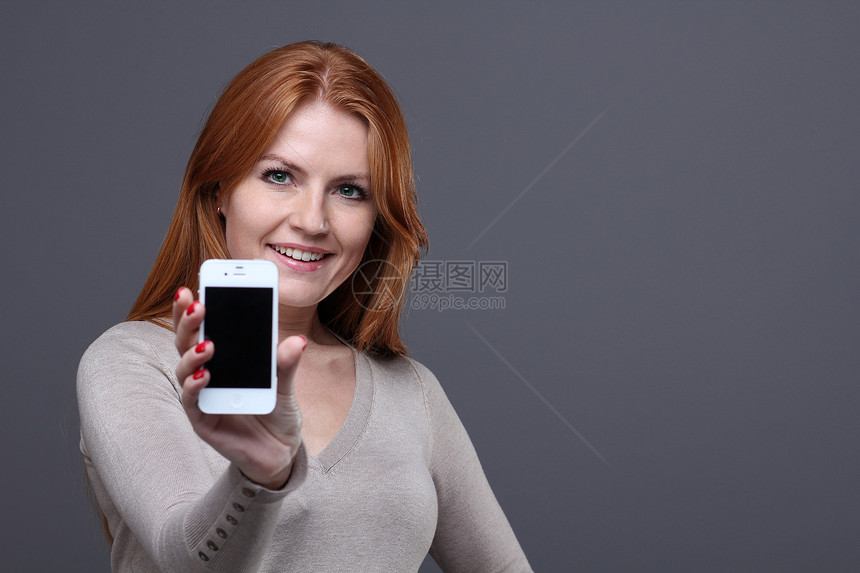 美丽的年轻女子产品女性成人手机技术红发女士展示微笑广告图片