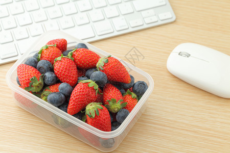 工作桌上的健康午餐箱食物水果办公室木头小吃键盘盒子时间笔记本老鼠背景图片