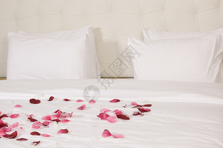 带有大床和红花的旅馆客房玫瑰酒店家具花瓣房间奢华毯子枕头红色花朵背景图片