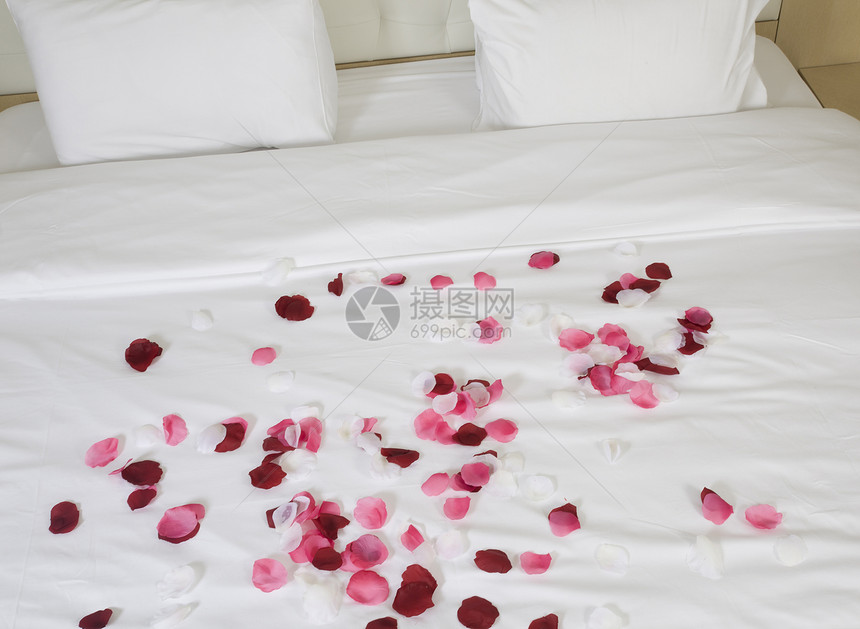 带有大床和红花的旅馆客房寝具花朵房子住宅家具枕头毯子酒店红色花瓣图片