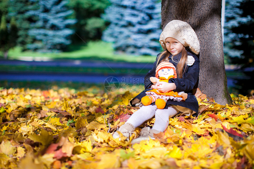 美丽的时装女郎 在阳光明媚的秋天坐在一棵有洋娃娃的山坡树下快乐孩子树叶婴儿橙子微笑树木晴天童年幸福图片