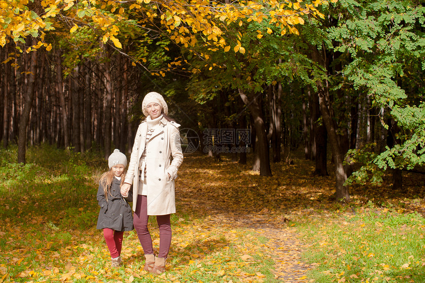 年轻母亲和她迷人的美丽女儿 在阳光温暖的天气下在秋天公园散步图片