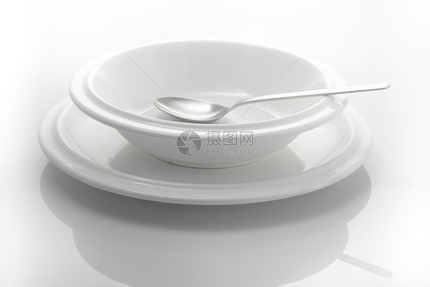 两个盘子和一勺勺子在白色背景上被孤立图片