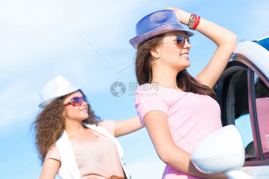 两名身戴墨镜的年轻美女微笑成人男性旅行女士树干假期男人太阳镜享受图片