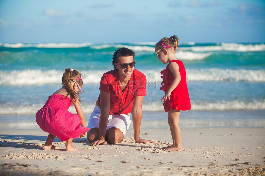 年轻父亲和他的可爱女儿们 在海滩上玩耍 在沙滩上玩海洋男性幸福女孩婴儿家庭热带海岸线爸爸假期图片